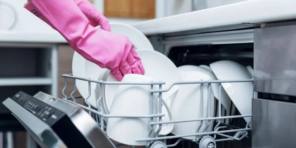 housewife taking out clean dishware from dishwasher royalty free image 903658124 1560287857 950x477 - نکات طلایی در مورد نحوه تمیز کردن ماشین ظرفشویی